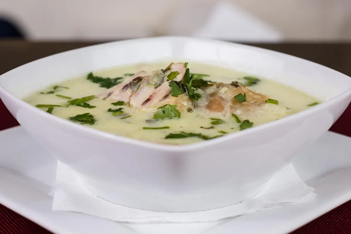 Tigela branca com sopa cremosa de frango e salsinha picada